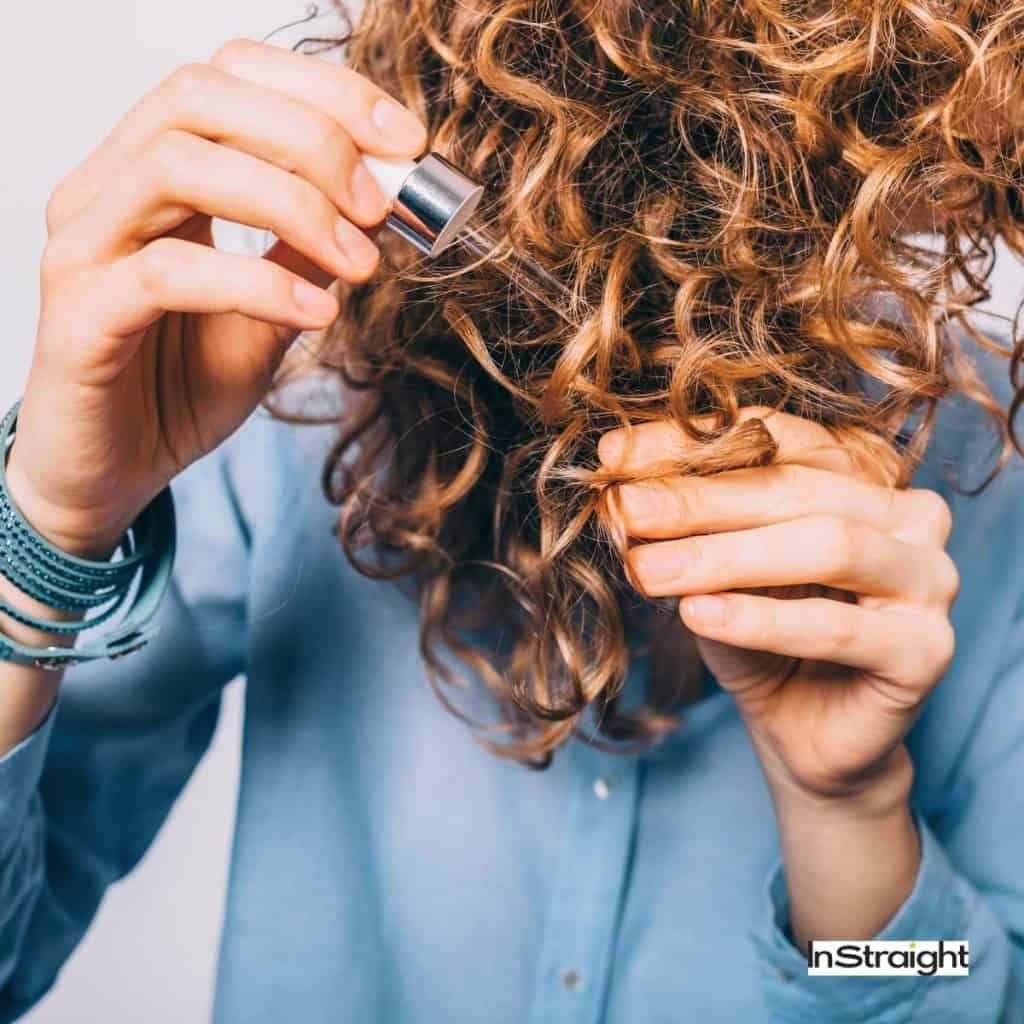 lady applying serum to her curly hair